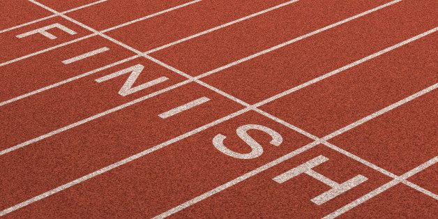 Finish Line as a business symbol of success in completing a planned strategy to achieve victory and reach the goals of financial freedom and wealth as a track and field background in perspective.