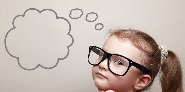 Cute thinking kid girl in glasses with empty bubble looking