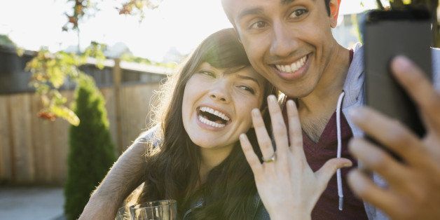 Enthusiastic couple taking selfie of engagement ring
