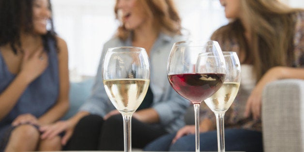 Women drinking wine and talking on sofa in living room