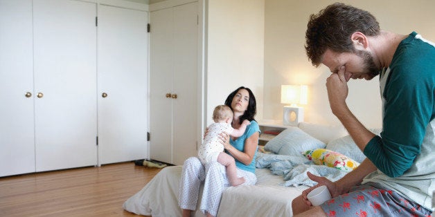 Parents and baby girl (9-12 months) in bedroom, man holding head