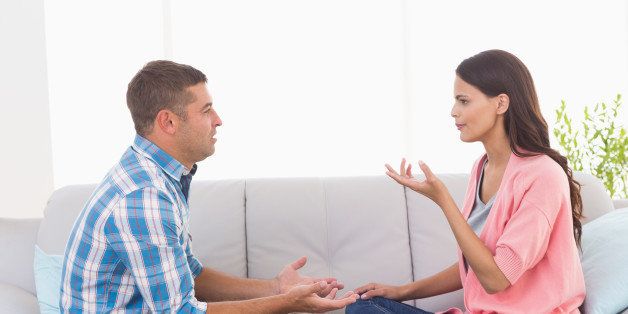 Side view of man and woman arguing while sitting on sofa at home