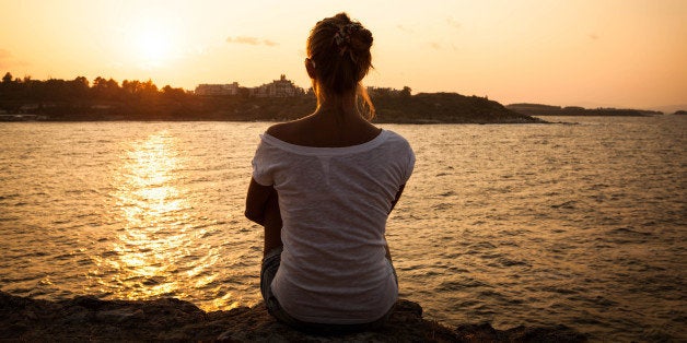 beautiful model girl sitting on the rock by the sea