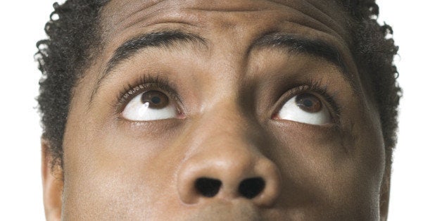 close up shot of a young adult male as he looks above his head and reacts with awe