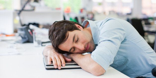 Businessman sleeping on laptop at desk in office