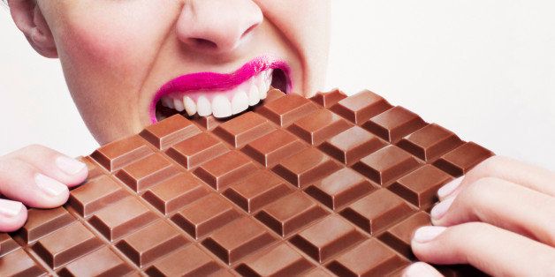 Woman in pink lipstick biting large chocolate bar