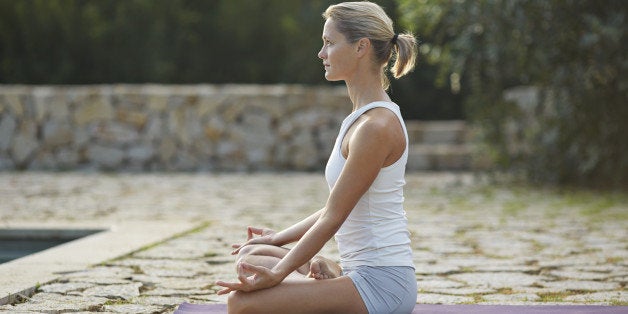 Beautiful woman practicing yoga by pool area in the mountains