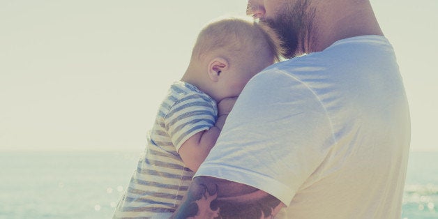 Close up of father holding baby son at beach