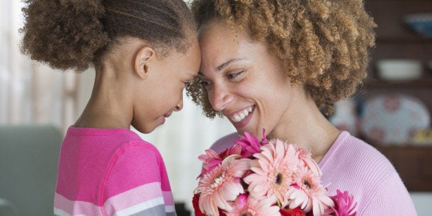 Black mother and daughter holding bouquet of flowers