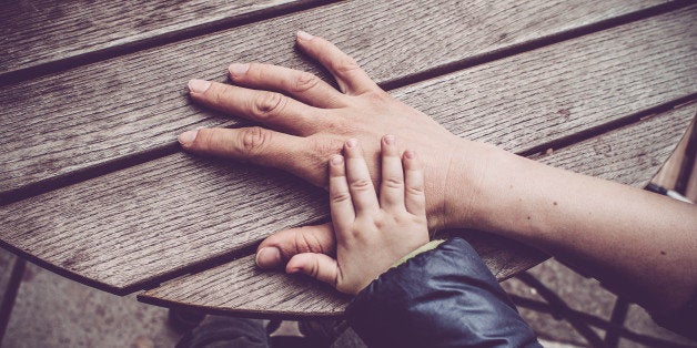 Mother and baby son holding hands on the table, outdoor photography. Italy, Gorizia.