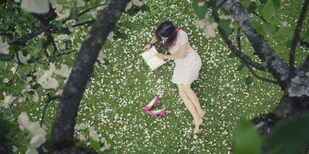 Young woman in a meadow full of apple petals - from above - reading a book - image cross processedmore photos of the same session: