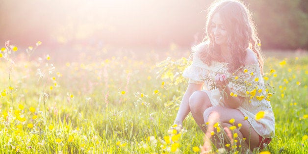 Woman picking flowers in a meadow at sunset, Hampstead Heath, London