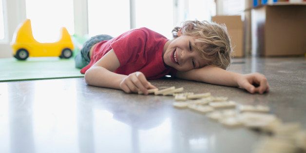 Smiling boy playing with dominoes on floor