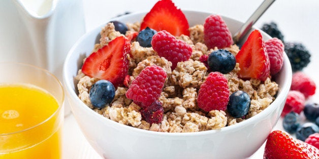 Macro close up of Healthy cereal breakfast with red fruits.Bowl of crunchy muesli and fresh orange juice.