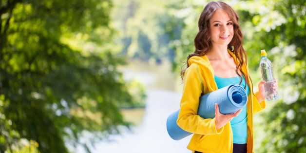Young beautiful woman holding a yoga mat and water bottle. Healthy lifestyle concept.