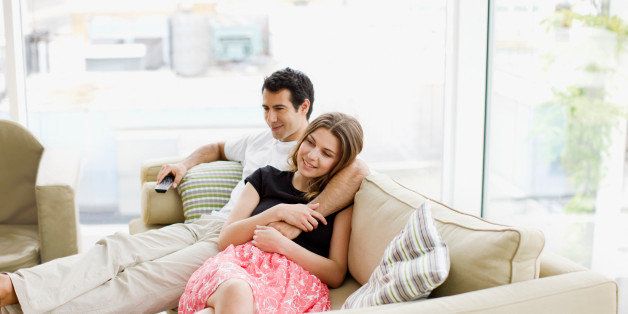 Couple sitting on sofa watching television