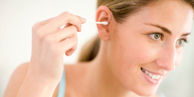 Young woman cleaning ear, smiling