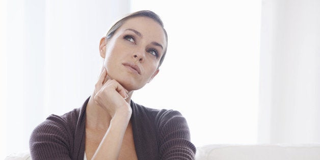 A young woman sitting on her couch looking thoughtful