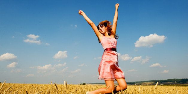 Happy woman jumping in golden field