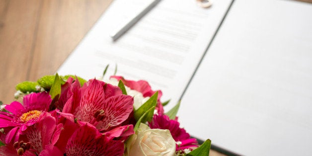 Marriage Contract with Pen and Bouquet of Fresh Beautiful Flowers on Top of a Wooden Table.