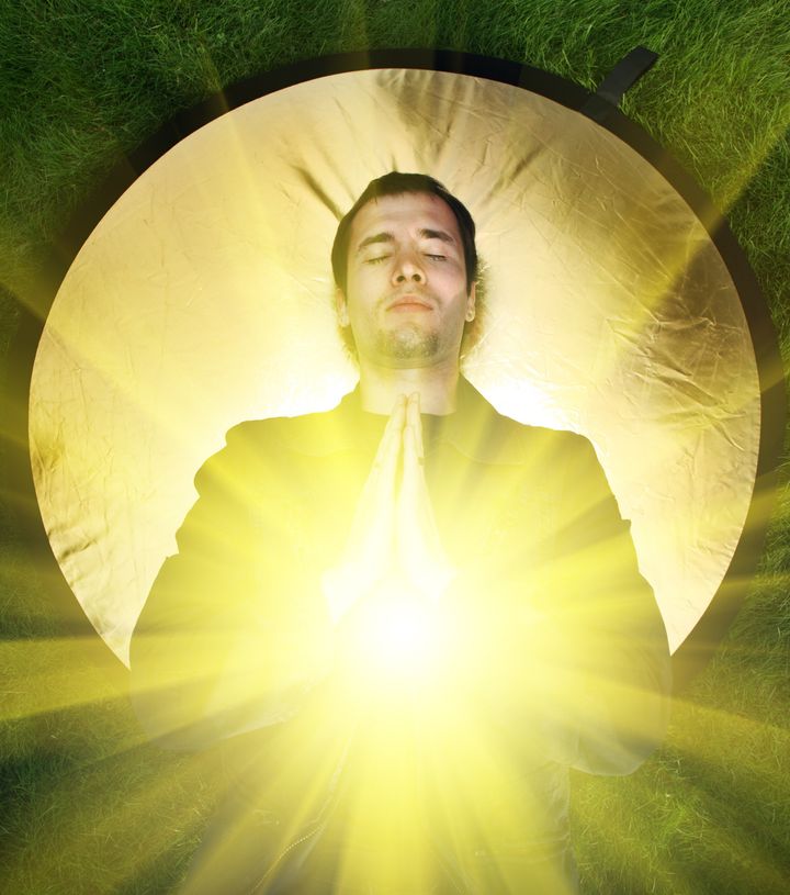 young man meditating with rays...
