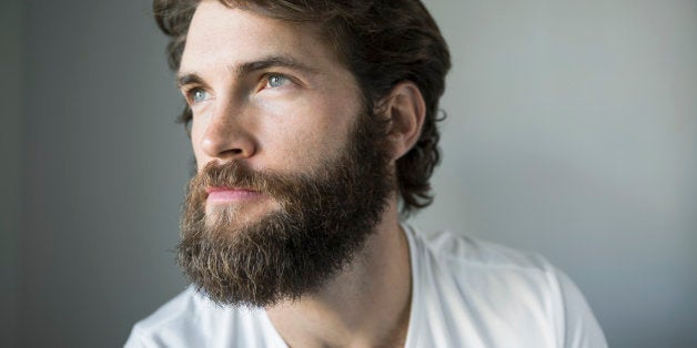 Pensive bearded brunette man looking away