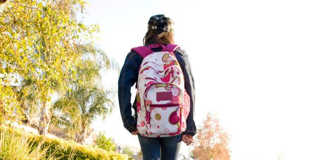 Girl wearing backpack walking down street