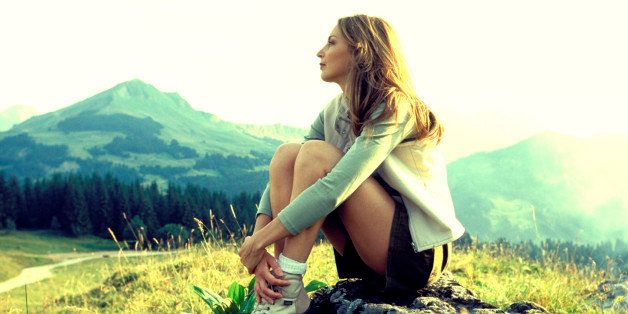 Woman sitting on mountainside