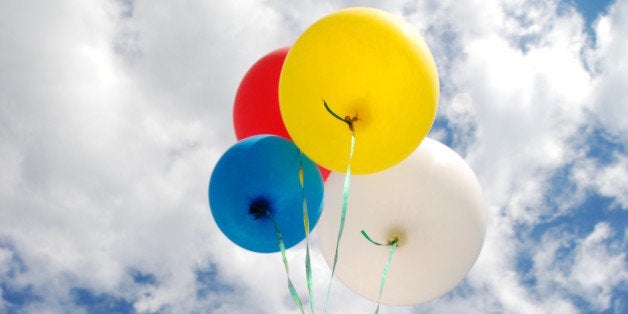 Balloons being released into the clouds on a bright summer day.