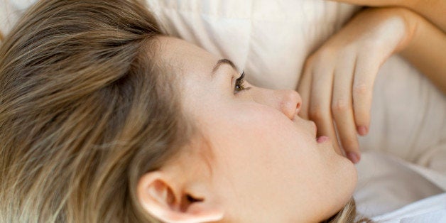 Woman lying down, looking away in thought