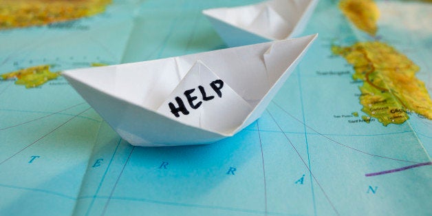 White paper boat onto world map with 'Help' sign on it.