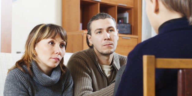 Parents scolding teenage child in home interior. Focus on woman