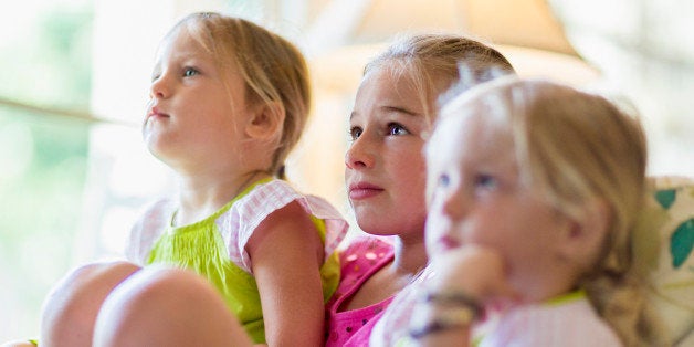 Caucasian girls watching television in armchair