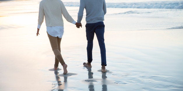 Young couple holding hands and walking on beach