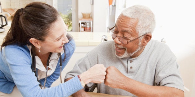 Nurse and older patient cheering in home