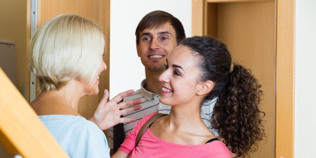 Happy mature mother meets son with his wife at doorway