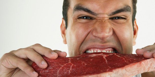 Hispanic man biting raw beef