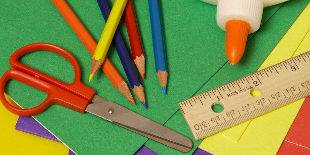 A close-up of paper, glue, colored pencils, scissors, and a ruler