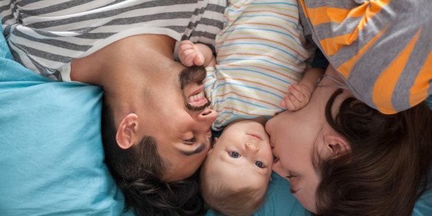 Young Parents With Their Son In Bed Spending Lovely Morning
