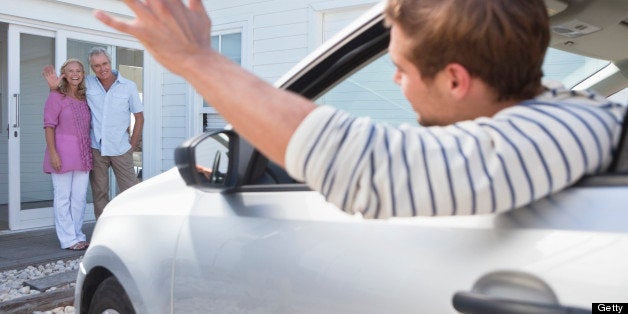 Young man in car waving goodbye to parents