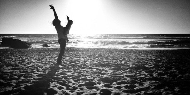 Side view of woman with baby raising hands on beach