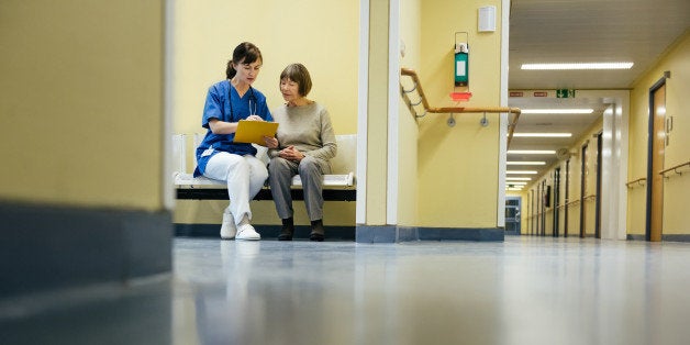 Mature female doctor and senior patient doing paperwork at hospital reception area