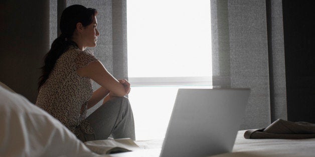 Sad woman looking out hotel window