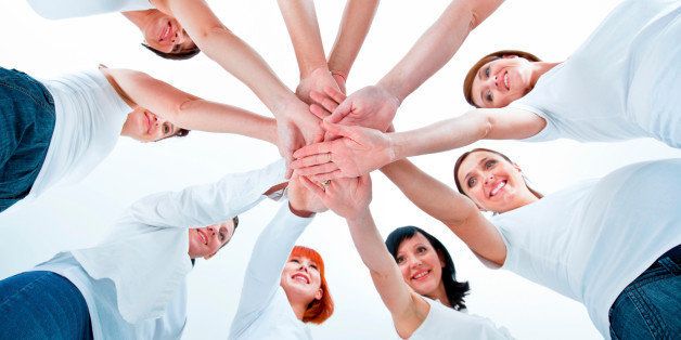 Teamwork concept. Group of women joining hands. Low angle view, white background.