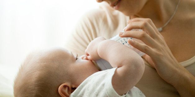 Mother feeding infant with baby bottle