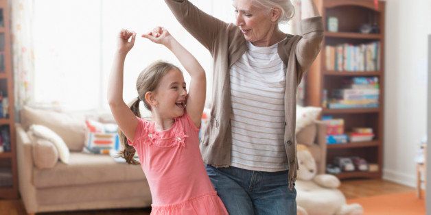 Caucasian grandmother and granddaughter dancing in living room