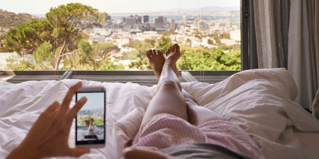 Cropped shot of a woman in bed taking a picture of the view from her bedroom