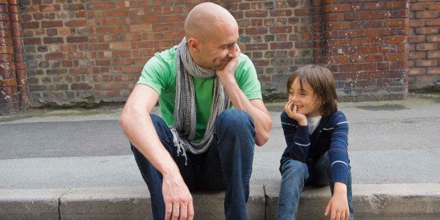 Father and son sitting on curb