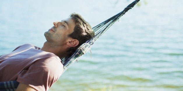 Serene man laying in hammock at lakeside