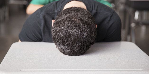 Portrait of a young high school student bored and frustrated with his head down on his desk
